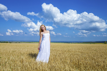 Fototapeta na wymiar Young beautiful woman in a long white dress is standing in a whe