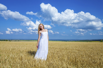 Young beautiful woman in a long white dress is standing in a whe