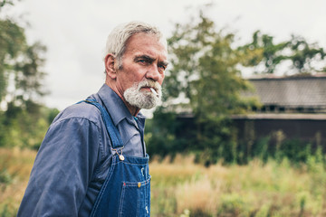 Pensive Senior Man Smoking Cigarette at the Farm