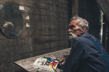 Fototapeta na wymiar Thoughtful Senior Man Sitting Inside a Farmhouse