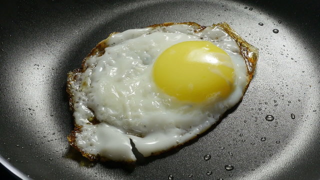 Chef lays out fried egg on a plate. 