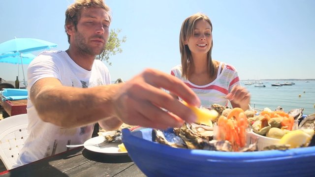 Couple at seafood outdoors restaurant tasting fresh oysters