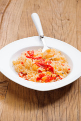 homemade rice stew with cod and peppers on ancient wooden table