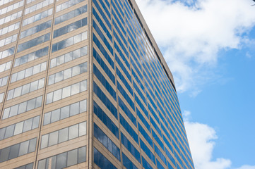 Close-up of facade of office building with sky reflection.