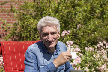 Mann trinkt in seinem Garten Kaffee