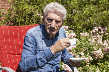Rentner trinkt Kaffee im Garten