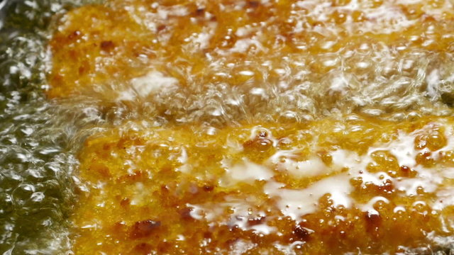 Fish corners cooking in a frying pan. 
