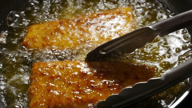 Fish corners cooking in a frying pan. 