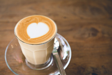 Cup of coffee with heart pattern  on wood table ( Filtered image