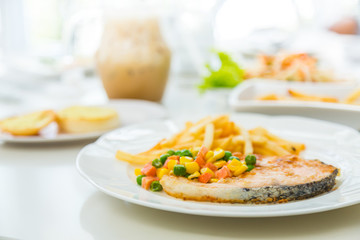 Grilled salmon steak meal served with salad and French fries
