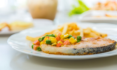 Grilled salmon steak meal served with salad and French fries