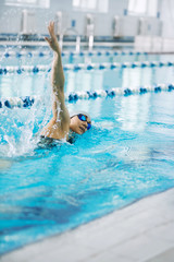 Young girl in goggles swimming front crawl stroke style