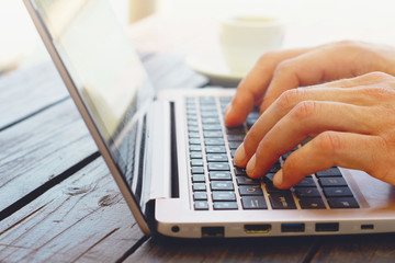 Close-up of male hands using laptop outside. Selective focus