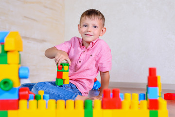 Happy young boy playing with his building blocks