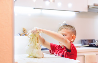 Young boy playing with dough while baking