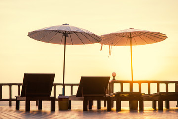 Terrace with a view on sea and sunset. Umbrellas and lounge chair in a sunlight.