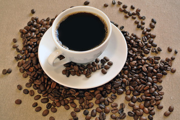 White porcelain coffee cup with coffee beans on cloth sack 