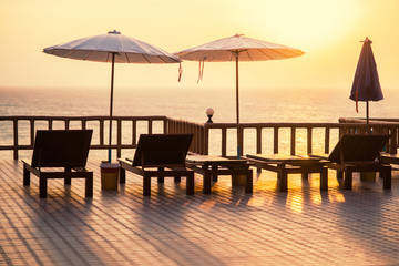 Terrace with a view on sea and sunset. Umbrellas and lounge chair in a sunlight.