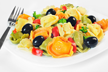 Salad made with tortellini, olives, broccoli, red pepper, on a plate with a fork, white background