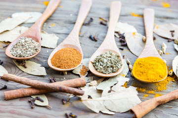 Spices in spoons on wooden table