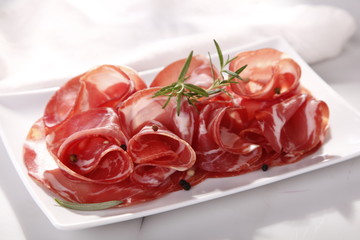Dried sausage on a plate and a wooden white board 