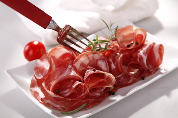 Dried sausage on a plate and a wooden white board 