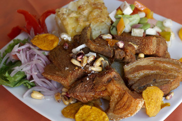 Peruvian food, Chicharron (fried pork) with potatoes, onion garnish, canchita.