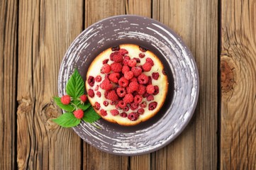 Homemade yummy round cake with fresh red raspberry and leaves in