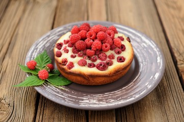 Homemade delicious round cake with fresh wild raspberries and le