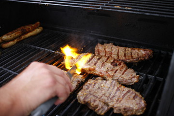 Steaks auf Grill, Hand und Zange und Feuer