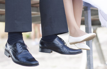 groom and bride sitting on wharf, theri shoes detail