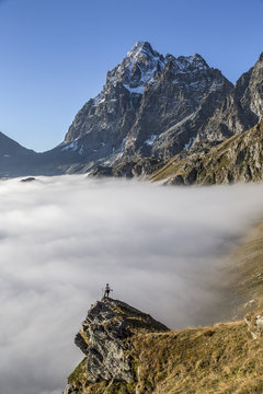A solitary hiker admiring the profile of the Monviso (Monte Viso) emerging from the fog, Piedmont