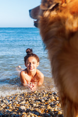 junges Mädchen am Strand mit unscharfem Hund im Vordergrund