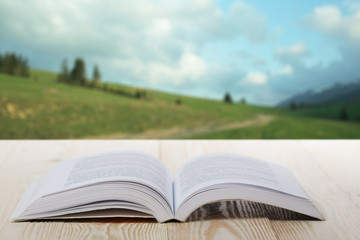 Open book on wooden table on natural blurred background
