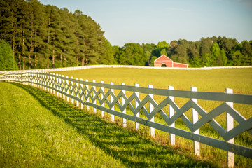  white fence leading up to a big red barn © digidreamgrafix