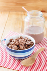 Chocolate cornflakes on wooden background with chocolate milk in