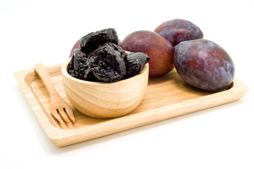 Delicious prunes in wooden bowl and fresh plums