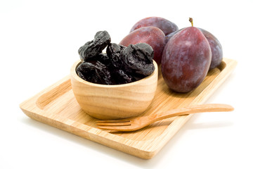 Delicious prunes in wooden bowl and fresh plums
