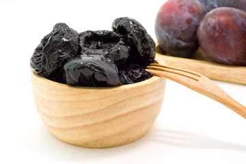 Delicious prunes in wooden bowl and fresh plums