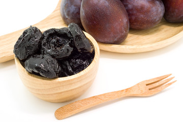 Delicious prunes in wooden bowl and fresh plums