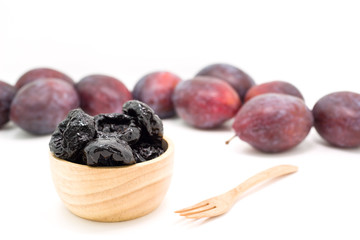 Delicious prunes in wooden bowl and fresh plums