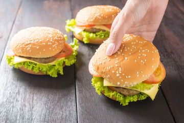 fast foods, Delicious burger in hands on wooden background