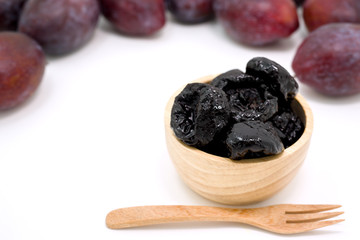 Delicious prunes in wooden bowl and fresh plums