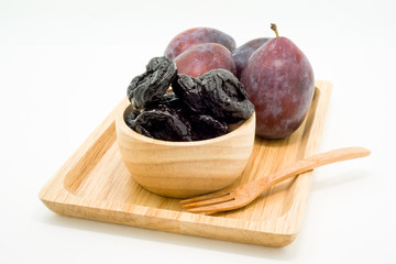 Delicious prunes in wooden bowl and fresh plums