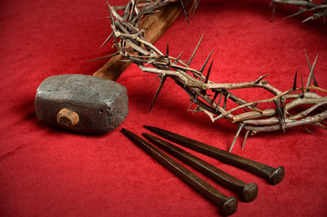 Crown of Thorns Nails and Hammer on Red Cloth