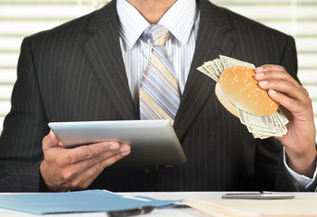 Greedy businessman with burger stuffed with money