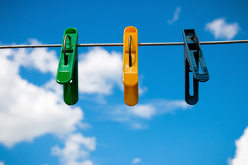colorful clothespins on a background of blue sky and white clouds