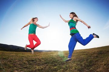 Fototapeta na wymiar Happy girls jumping in nature, image shot with fish-eye lens