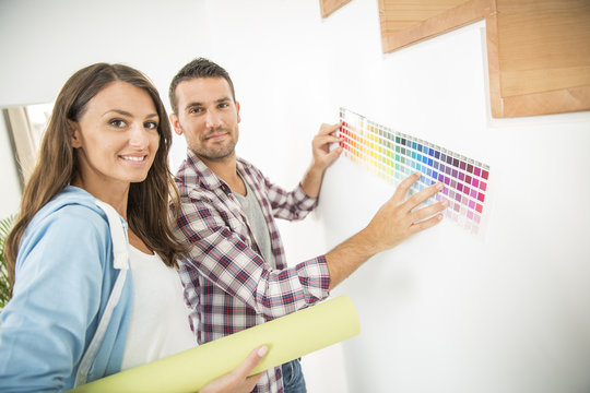 Young couple choosing paint color and pent paper