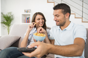 Young couple with popcorn watching movie at home